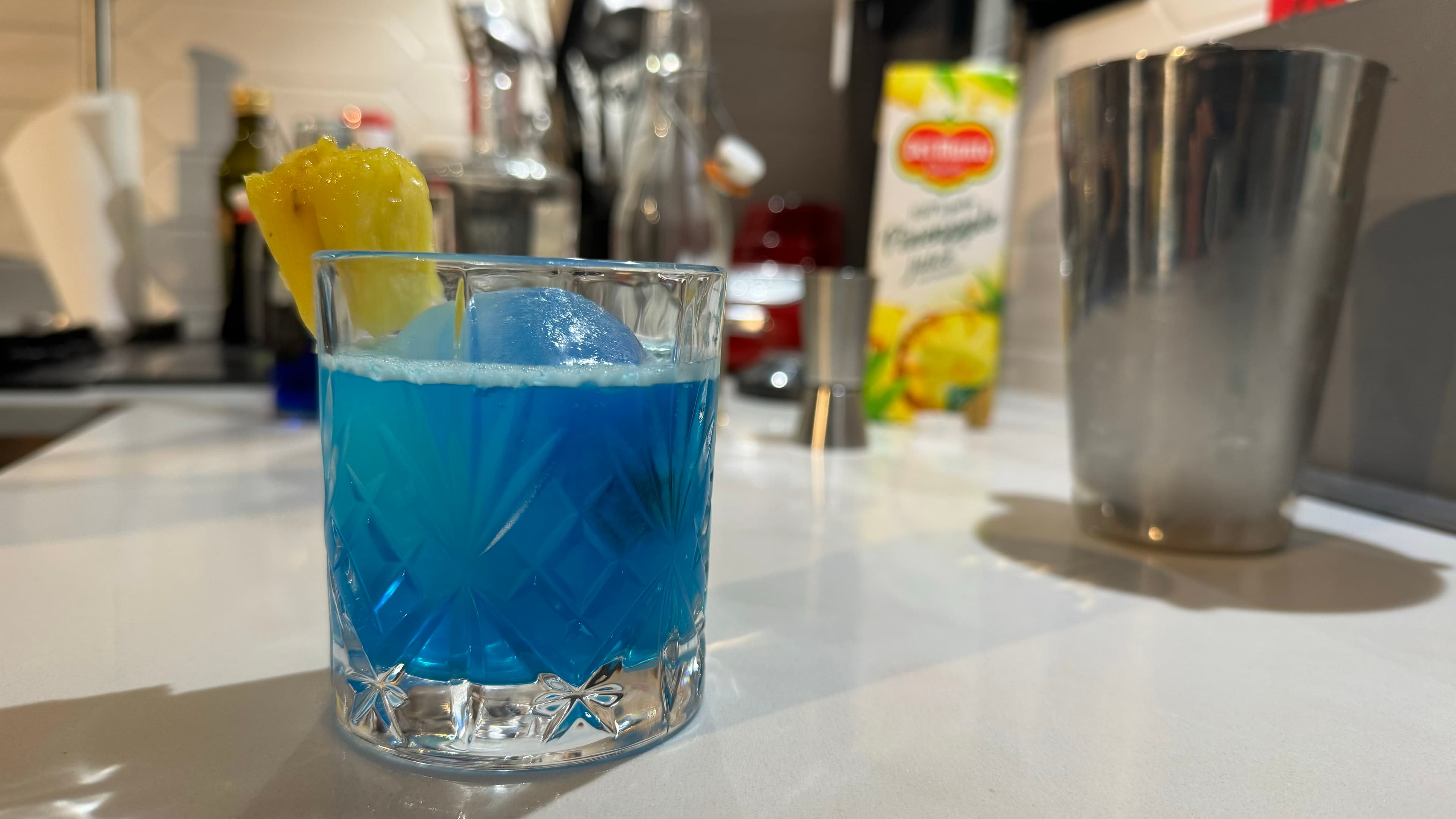 Image of a blue cocktail in a tumblr with a pinapple chunk on its rim