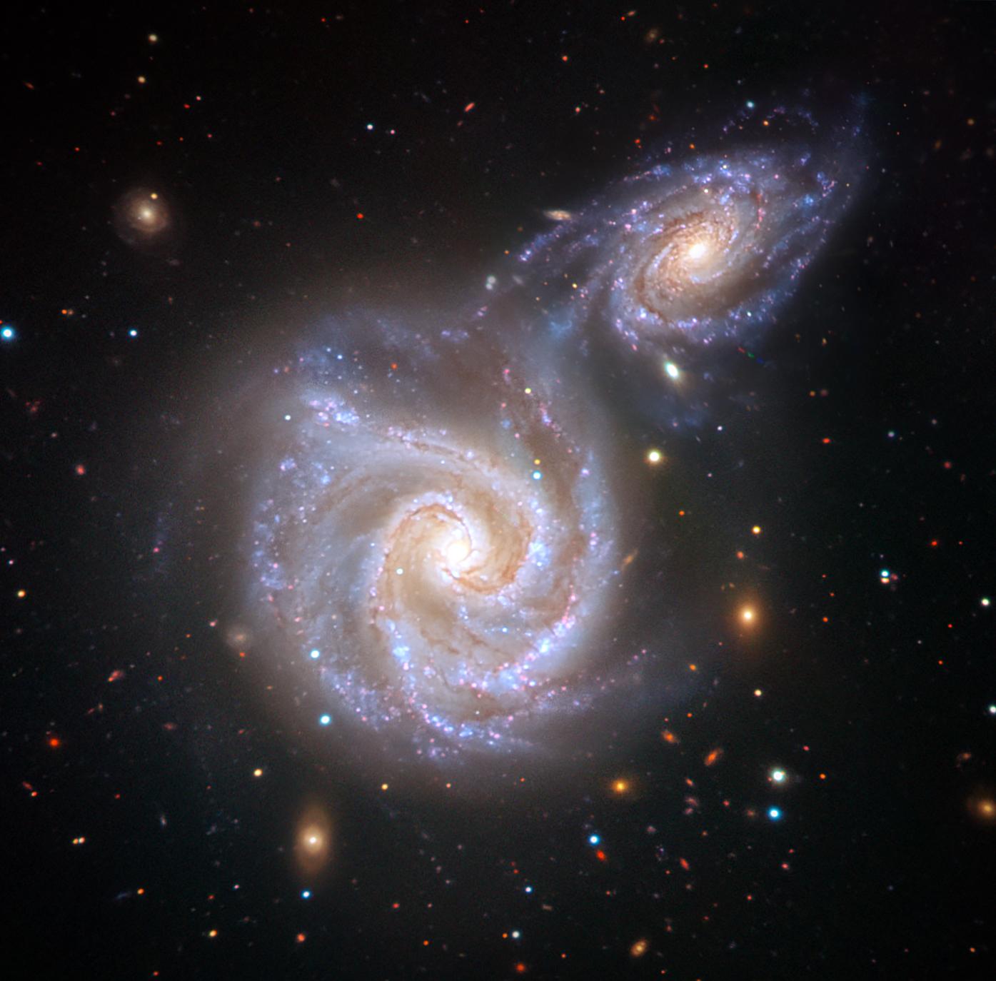 Artist's impression of two spiral galaxies one big and one much smaller about to collide