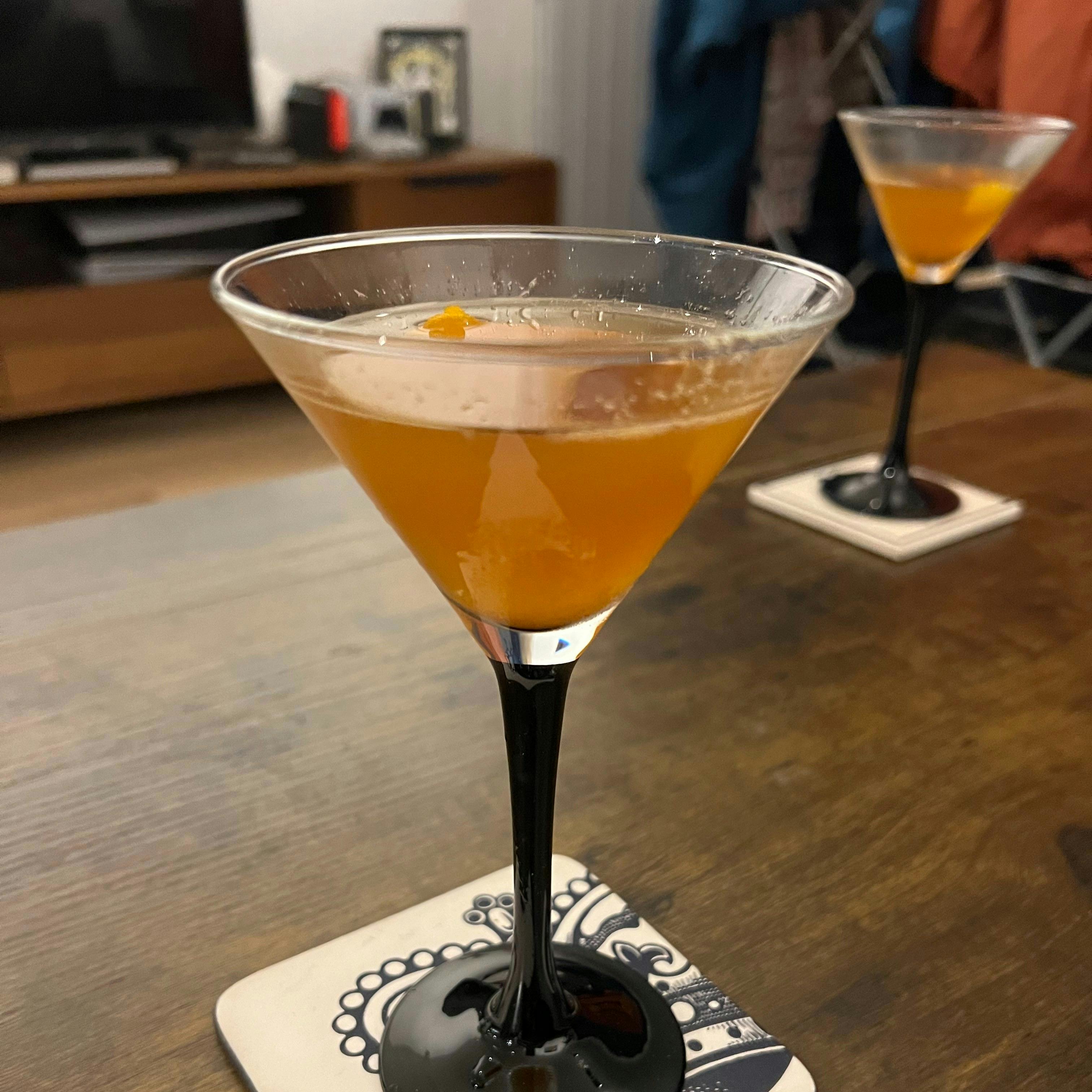 A martini glass with an orange cocktail in it